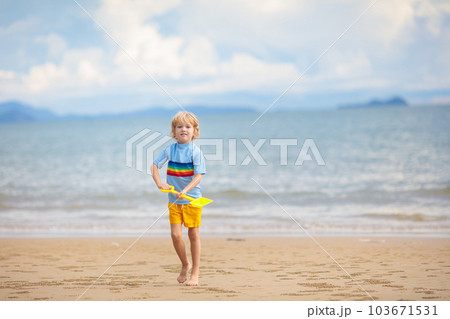 Kids play on tropical beach. Sand and water toy. 103671531
