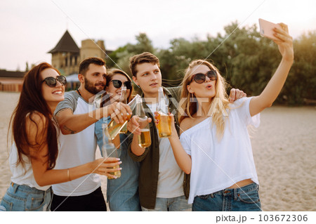 Group of people doing selfie with phone at the beach. Young friends enjoy summer party together. 103672306