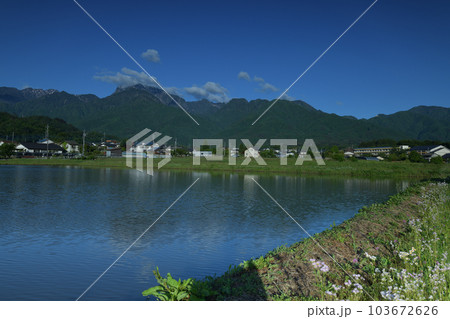 北杜市白州町、田植え待つ水面に映る南アルプスの山並みと麓の街並み 103672626