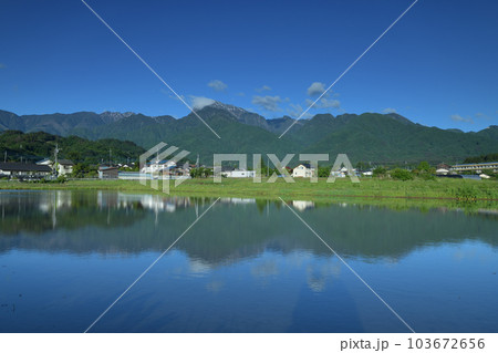 北杜市白州町、田植え待つ水面に映る南アルプスの山並みと麓の街並み 103672656