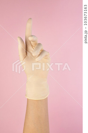 Female hand in a white latex glove on a pink background. The concept of maintaining sterility in cosmetology 103673163