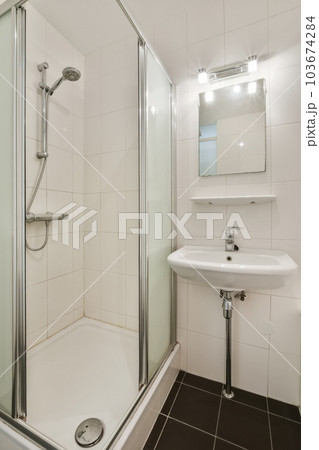 a bathroom with a sink, mirror and shower stall in the corner area on the left side of the room 103674284