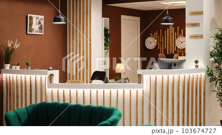Empty stylish rustic welcoming hotel lounge interior with luxurious green chairs and sofa ready for arriving guests. Travel vacation accommodation check in counter desk, slow motion 103674727