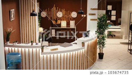 Empty stylish modern resort lobby interior with cozy furniture and warm fireplace ready to welcome guests. Travel accommodation hotel lounge with check in front reception desk 103674735