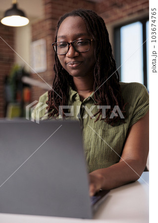 Focused african american entrepreneur working from home typing and looking at laptop screen in home living room. Portrait of freelancer doing remote work on portable computer at desk. 103674765