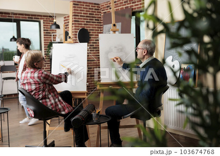 Mature couple man and woman learning drawing at group art class in modern studio. Senior family wife and husband attend creative workshop, learn new skills together. Creative hobby for elderly people 103674768