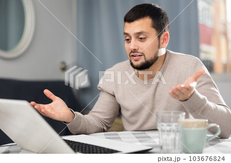 Smiling young man making video call on laptop at home 103676824