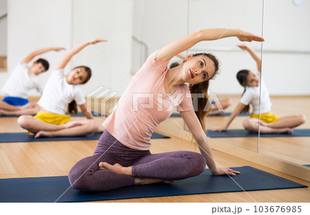 Woman sitting in lotus pose and stretching on family yoga training 103676985