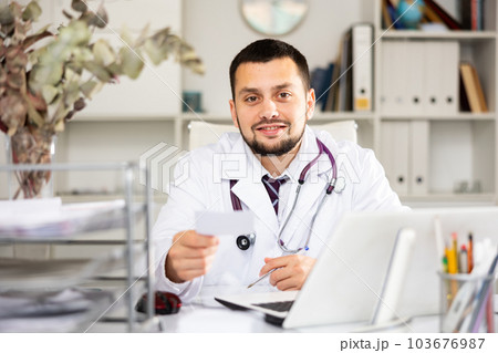 Portrait of male doctor giving treatment sheet 103676987