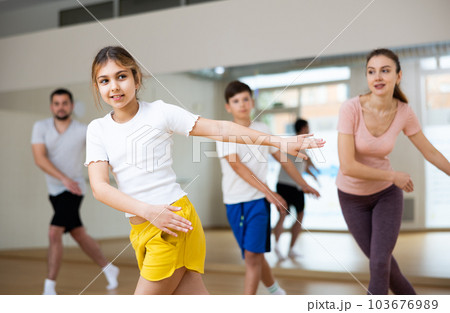Cheerful teen girl practicing vigorous dance in class with family 103676989