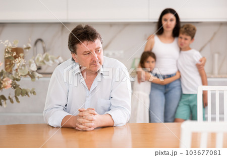 Wife and children stand behind dad and are afraid to ask about current problem 103677081