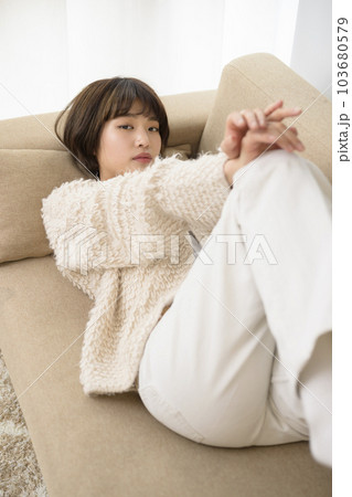 ソファに寝そべる若い女性 103680579