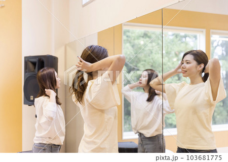 レッスンスタジオの鏡の前で髪の毛を縛る若い女性 103681775