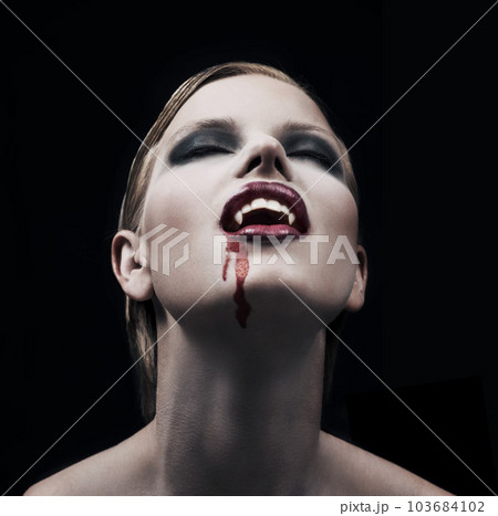 Blood, woman and vampire with fantasy, fangs and lady against a dark studio background. Female person, supernatural being and girl mystic, aesthetic and monster with creativity, demon and character 103684102