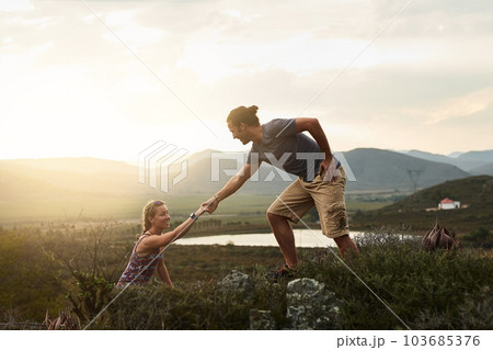 Man helping woman while hiking, fitness and couple outdoor trekking in nature or countryside for exercise and travel. Young people hike together, support and adventure with date, bonding and workout 103685376