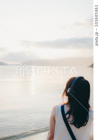 ヘッドフォンをして海を眺める女性 103685861