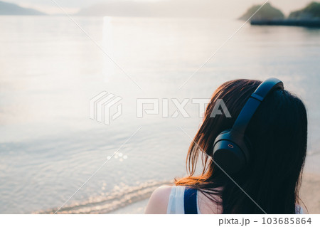 ヘッドフォンをして海を眺める女性 103685864