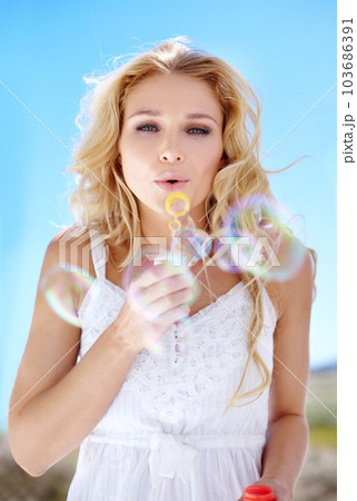 Summer, portrait and a woman blowing bubbles for happiness, fun and playful in nature. Beautiful, spring and a young lady with bubbles, playing and enjoying childlike energy in a garden or park 103686391