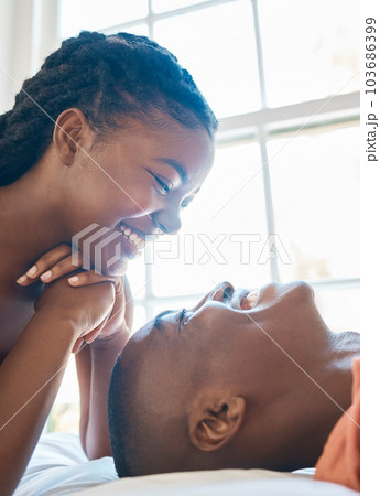 Happy african american couple laughing while looking into each others eyes. Couple sharing and intimate moment while bonding and spending time together at home 103686399