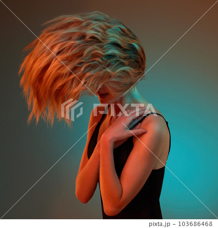 Whip it real good. Studio shot of an unrecognizable young woman posing against a blue background. 103686468