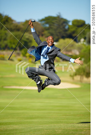 Man, golf and jump for celebration, excited face or portrait for winning, achievement or goal outdoor. African businessman, golfer and corporate winner at sport pitch with suit, freedom or fitness 103686555