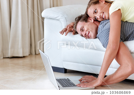 Could this be called online dating. A young woman lying on her boyfriends back as they both look at a laptop screen. Could this be called online dating. A young woman lying on her boyfriends back as they both look at a laptop screen. 103686869