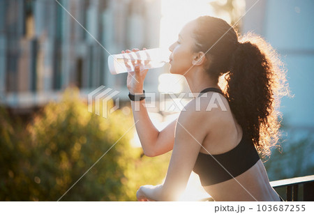 Water breaks are important. Cropped shot of an attractive young female athlete drinking water while out for a run in the city. 103687255