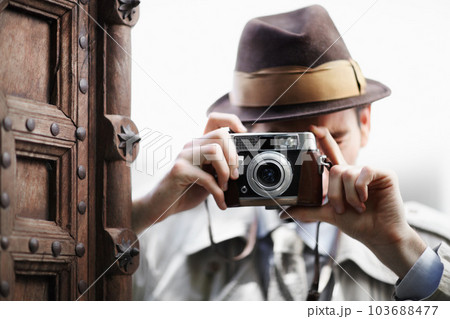 Detective, camera and spy with man in studio for surveillance, reporter and investigation. Photography, press and secret with male agent on white background for vintage, paparazzi and journalist 103688477