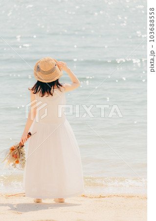 海辺でドライフラワーを持って佇む女性 海辺でドライフラワーを持って佇む女性 103688558