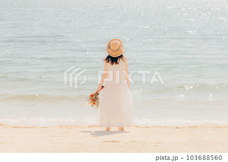 海辺でドライフラワーを持って佇む女性 103688560