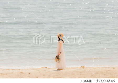 海辺でドライフラワーを持って佇む女性 103688565