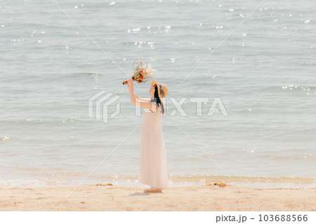 海辺でドライフラワーを持って佇む女性 103688566