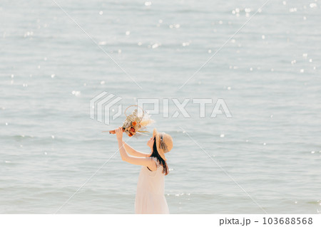 海辺でドライフラワーを持って佇む女性 海辺でドライフラワーを持って佇む女性 103688568