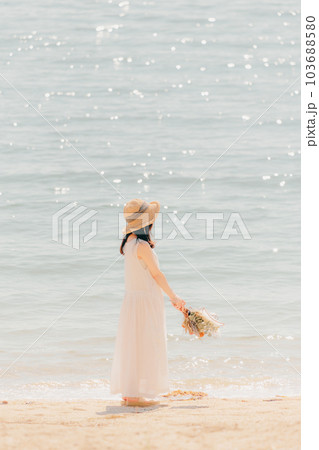 海辺でドライフラワーを持って佇む女性 103688580