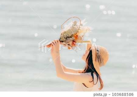 海辺でドライフラワーを持って佇む女性 海辺でドライフラワーを持って佇む女性 103688586