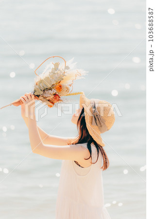 海辺でドライフラワーを持って佇む女性 海辺でドライフラワーを持って佇む女性 103688587