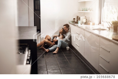 The familiar comforts of home. an affectionate young couple sitting on the kitchen floor. The familiar comforts of home. an affectionate young couple sitting on the kitchen floor. 103688678