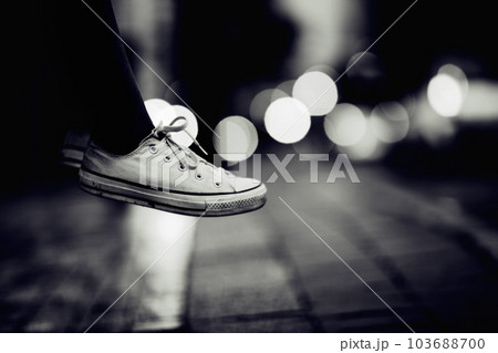 Closeup, monochrome and sneakers outdoor, city and lights with creativity, road and artistic. Zoom, person or model with shoes, street and grey with footwear, night or creative with fashion or travel 103688700