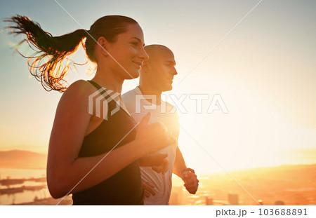 Sunrise, fitness and happy couple running as workout or morning exercise for health and wellness together. Sport, man and woman runner run with athlete as training in a city for sports with energy Sunrise, fitness and happy couple running as workout or morning exercise for health and wellness together. Sport, man and woman runner run with athlete as training in a city for sports with energy 103688891