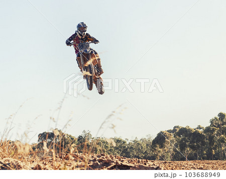 Ripping through the air. a motocross rider coming over a jump during a race. Ripping through the air. a motocross rider coming over a jump during a race. 103688949