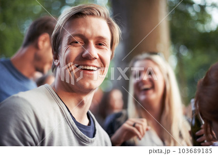 Enjoy an outdoor event. Portrait of a happy young man enjoying an outdoor festival with his friends. 103689185