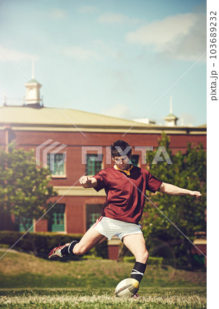 Rugby, sports and man kick a ball outdoor on a pitch with green lawn or grass. Male athlete person in action playing in sport competition, game or training match for fitness, workout or exercise 103689232