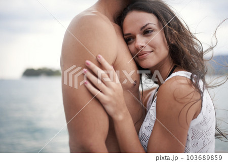 I always feel safe with him. an intimate young couple enjoying a warm embrace by the waters edge. I always feel safe with him. an intimate young couple enjoying a warm embrace by the waters edge. 103689859