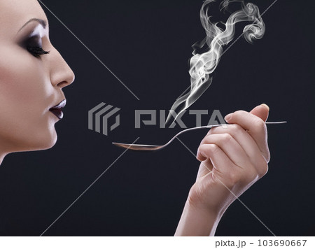 Makeup, hot and woman blowing a spoon with steam in studio with gothic, cool and danger aesthetic. Mockup, art and female posing with smoke and utensil creative, punk and edgy on black background Makeup, hot and woman blowing a spoon with steam in studio with gothic, cool and danger aesthetic. Mockup, art and female posing with smoke and utensil creative, punk and edgy on black background 103690667