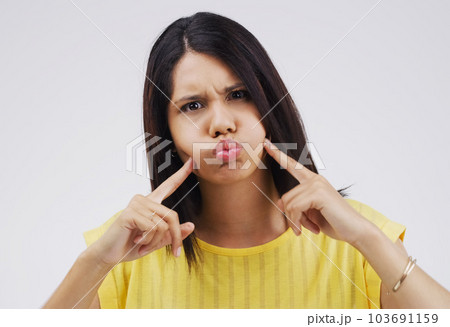 Am I making you laugh yet. Studio shot of a young woman making a funny face against a gray background. Am I making you laugh yet. Studio shot of a young woman making a funny face against a gray background. 103691159