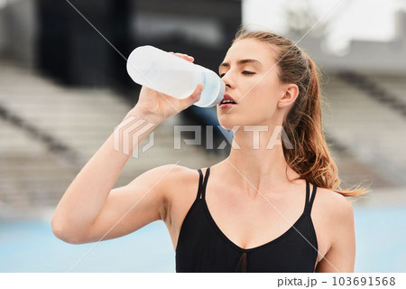 Fitness, woman and runner drinking water for hydration after running exercise, workout or athletic training. Sports, nutrition or thirsty female athlete in rest with drink for natural sustainability Fitness, woman and runner drinking water for hydration after running exercise, workout or athletic training. Sports, nutrition or thirsty female athlete in rest with drink for natural sustainability 103691568