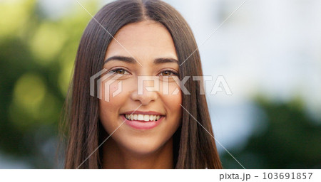 Portrait of a beautiful girl standing and commuting in the city. One happy and stylish young female smiling and relaxing downtown. Trendy young woman showing her teeth, laughing and traveling in town 103691857