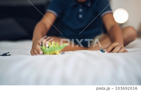 Dinosaurs are his favourite animals. an unrecognizable boy playing with dinosaurs while sitting on his bed. Dinosaurs are his favourite animals. an unrecognizable boy playing with dinosaurs while sitting on his bed. 103692016