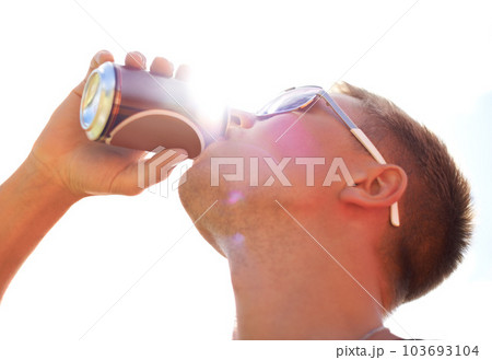 Enjoying a beer. Closeup of a young man wearing sunglasses drinking a beer outside. 103693104