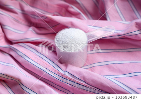 Detergent powder in measuring spoon on cloth before washing. Laundry concept. 103693487